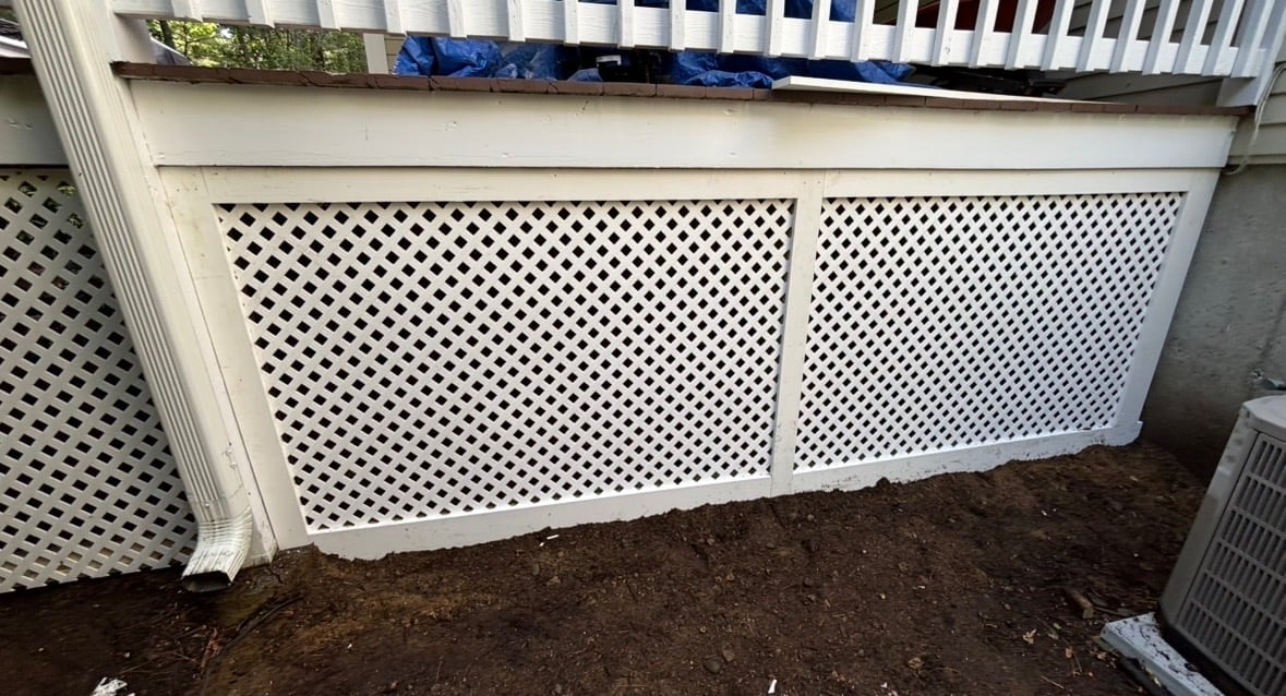 White lattice deck skirting panels installed around a raised deck foundation with dark mulch below